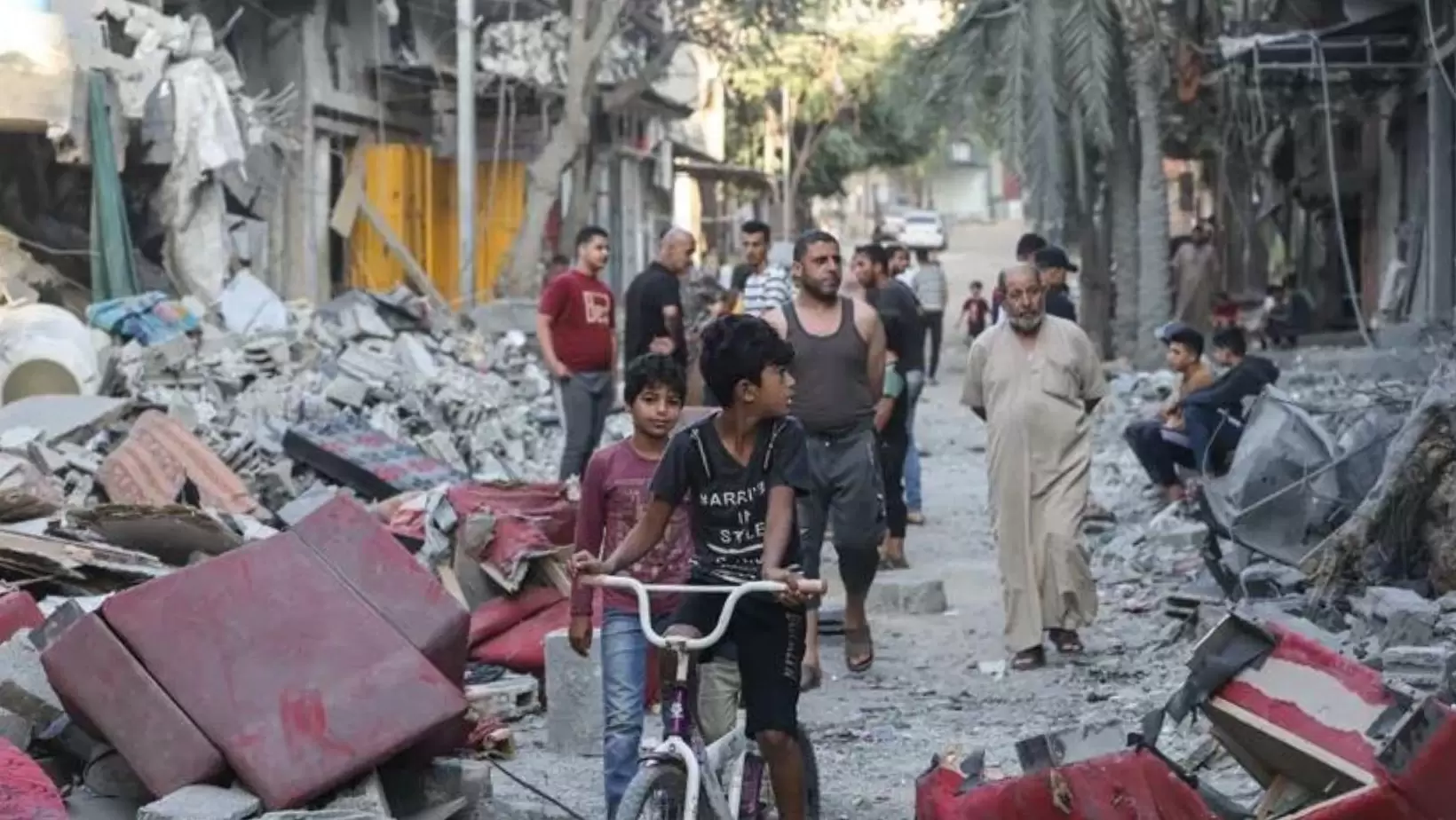 Crianças andam de bicicleta em meio a escombros Gaza