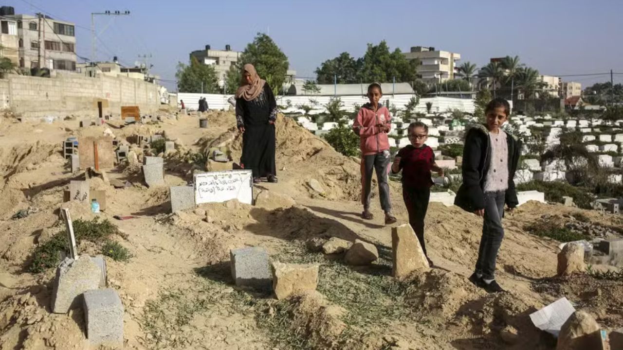 Mulher e filhas buscam parentes enterrados no cemitério improvisado em Gaza