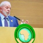 Na imagem Luis Inácio Lula da Silva aparece de terno azul, braços flexionados e discursa para a União Africana