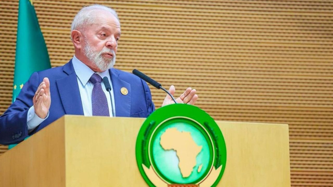 Na imagem Luis Inácio Lula da Silva aparece de terno azul, braços flexionados e discursa para a União Africana