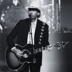 Músico country Toby Keith aparece em cima do palco cantando e tocando violão durante show