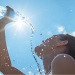 mulher jogando água no rosto para aliviar calor