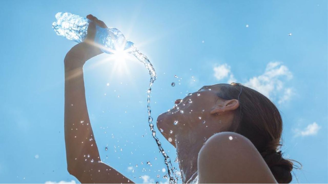 mulher jogando água no rosto para aliviar calor