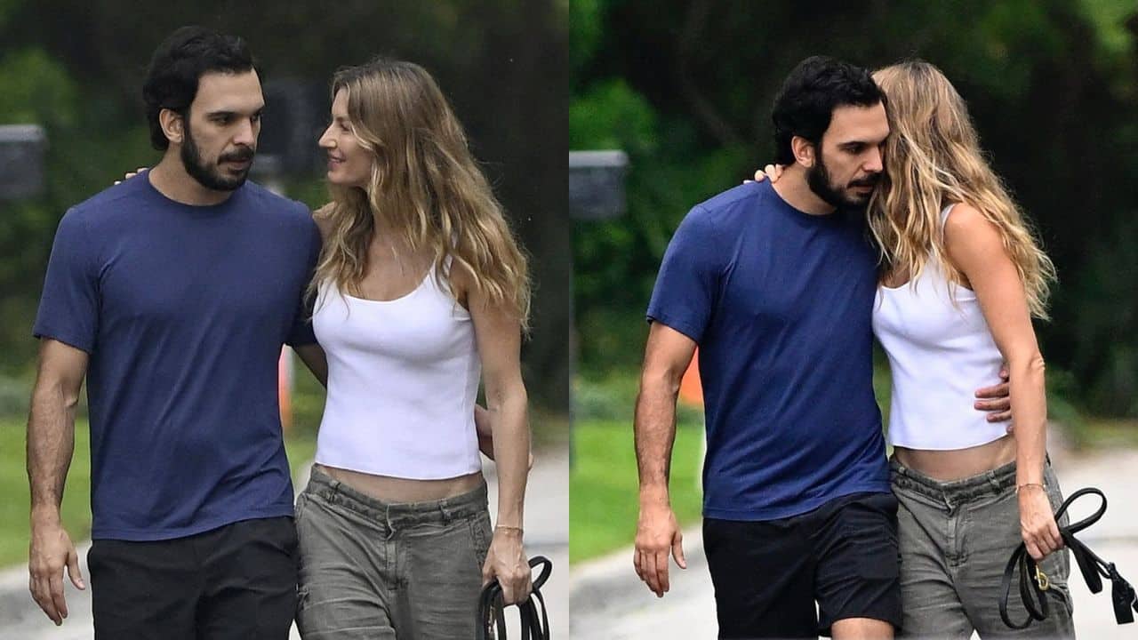 Gisele Bündchen e Joaquim Valente caminhando abraçados em jardim. Ela está vestindo uma regata branca e uma calça verde musgo. Joaquim veste uma camiseta em tom azul escuro e calça preta.