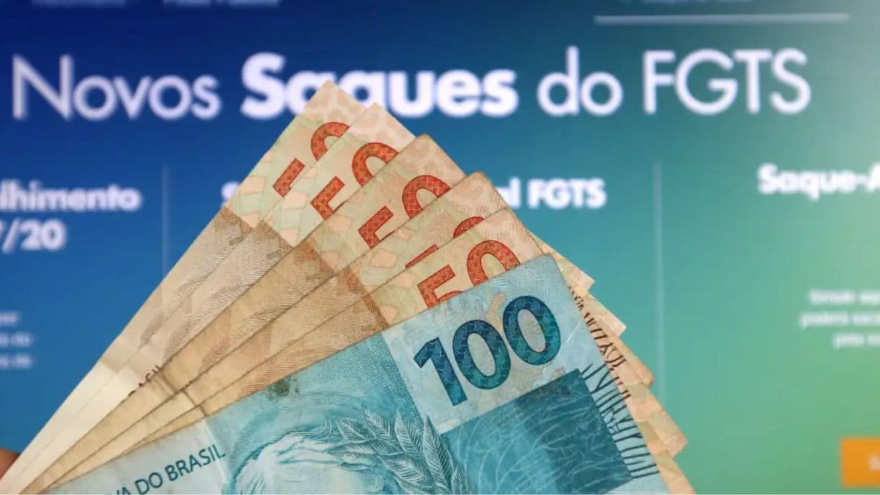 Notas de 100 e 50 reais em frente a um banner informativo sobre os novos saques do FGTS