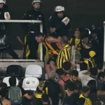 Policial batendo em torcedor no meio de confusão em jogo