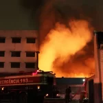 Caminhão do Corpo de Bombeiros combate incêndio no Shopping 25 de Março, no Brás, São Paulo, em meio a intensas chamas e fumaça densa