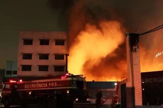 Caminhão do Corpo de Bombeiros combate incêndio no Shopping 25 de Março, no Brás, São Paulo, em meio a intensas chamas e fumaça densa