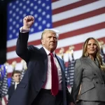 Donald Trump, ao lado de sua esposa Melania Trump, ergue o punho em sinal de vitória, com a bandeira dos Estados Unidos ao fundo, durante o discurso de celebração por sua reeleição à presidência