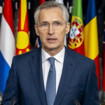 Jens Stoltenberg, secretário-geral da OTAN, em coletiva de imprensa com bandeiras dos países membros ao fundo