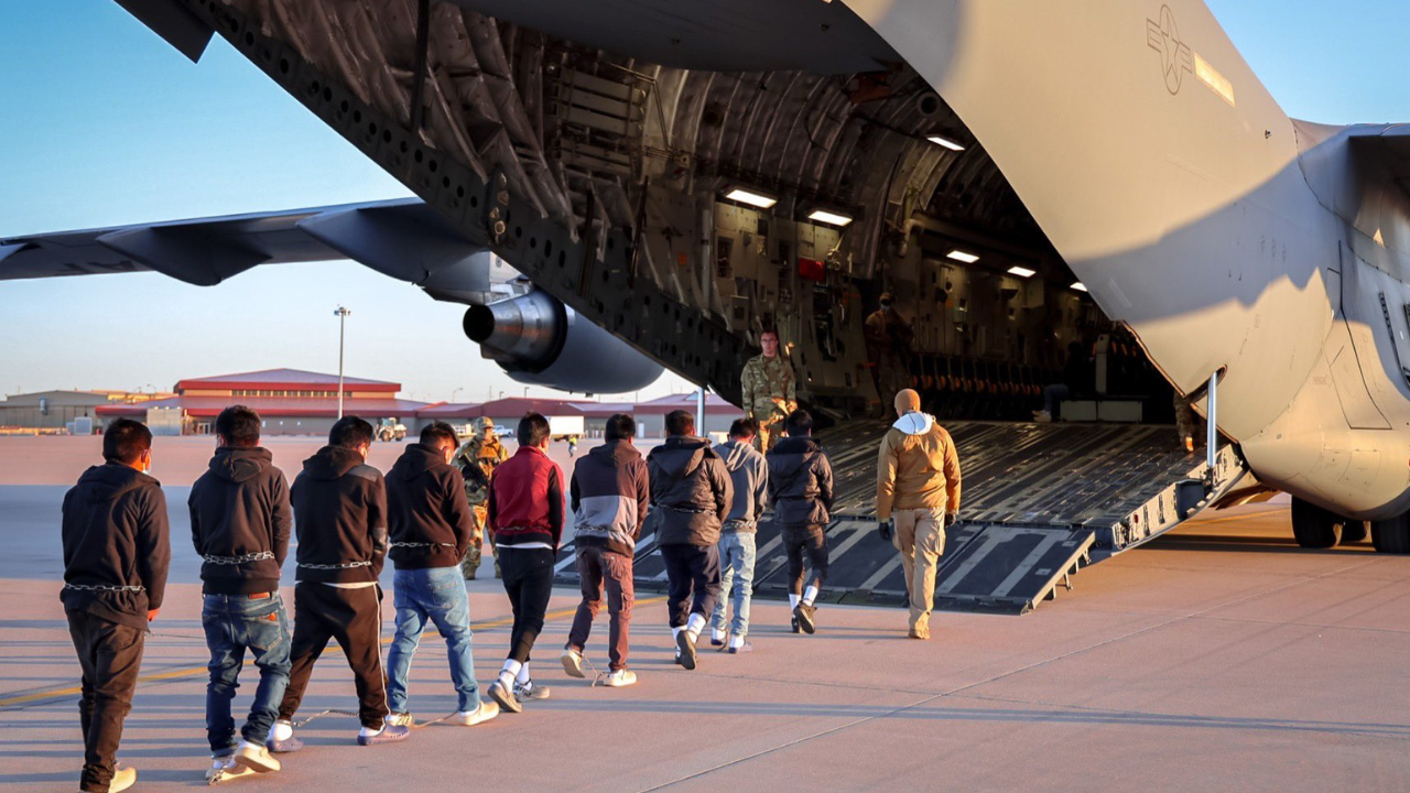 Imigrantes brasileiros, deportados em virtude da ordem decretada por Donald Trump, aguardam em fila para embarcarem em avião da força aérea americana rumo a Belo Horizonte