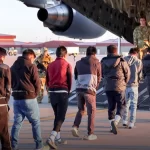 Deportados acorrentados entrando em avião dos EUA