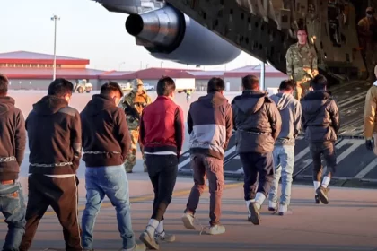 Deportados acorrentados entrando em avião dos EUA