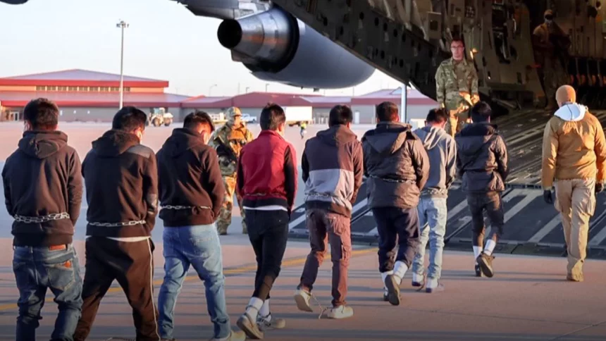 Deportados acorrentados entrando em avião dos EUA