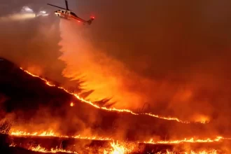 Helicóptero sobrevoando área sendo atingida pelo grande incêndio de Los Angeles, na tentativa de controlar as chamas