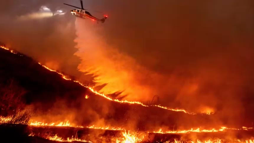 Helicóptero sobrevoando área sendo atingida pelo grande incêndio de Los Angeles, na tentativa de controlar as chamas