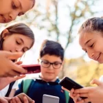 Foto mostrando grupo de crianças com celulares na mão, ocasião que a sociedade busca combater cada vez mais, devido aos prejuizos científicamente comprovados que o aparelho causa na vida e na formação dos jovens