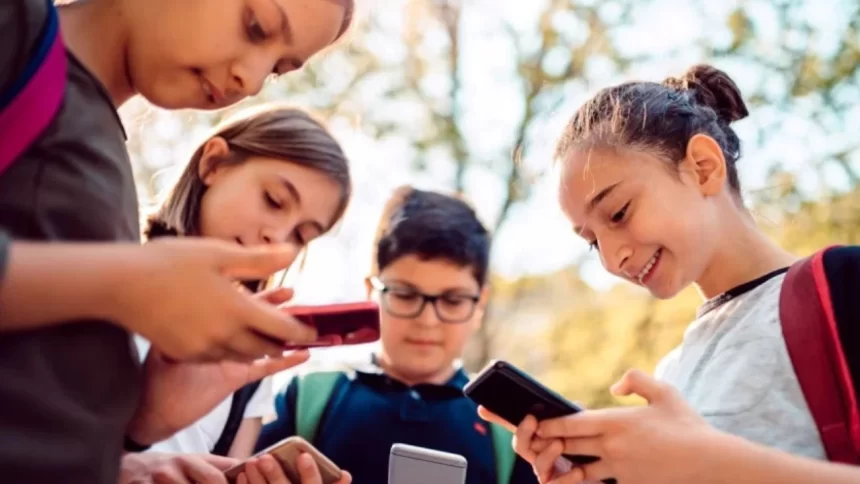 Foto mostrando grupo de crianças com celulares na mão, ocasião que a sociedade busca combater cada vez mais, devido aos prejuizos científicamente comprovados que o aparelho causa na vida e na formação dos jovens