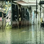 Rua alagada, com pessoas com água nos joelhos