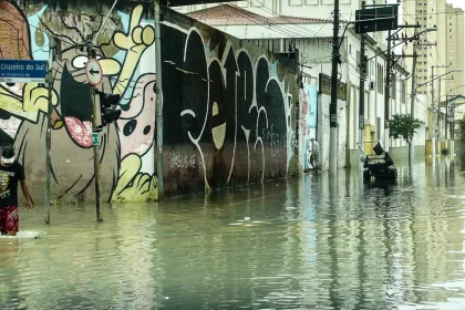 Rua alagada, com pessoas com água nos joelhos