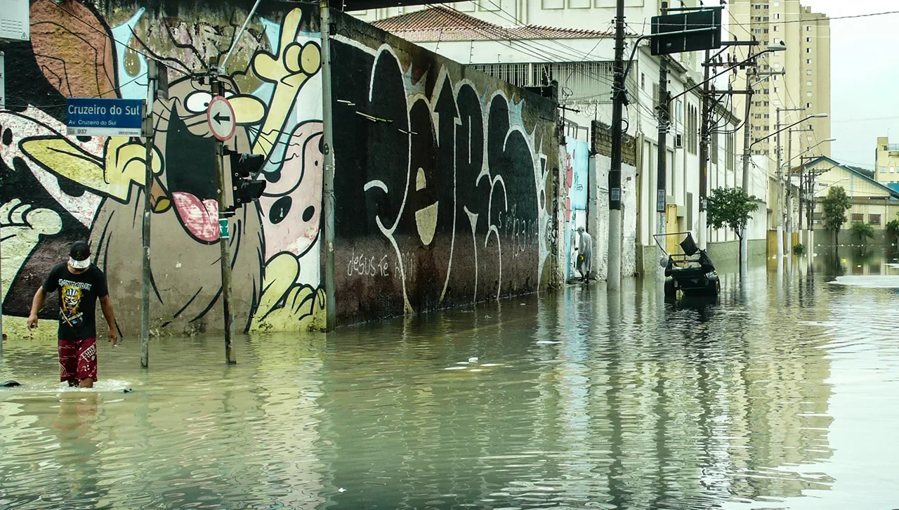 Rua alagada, com pessoas com água nos joelhos