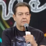 Faustão com microfone na mão apresentando o programa de domingo