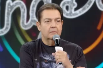 Faustão com microfone na mão apresentando o programa de domingo