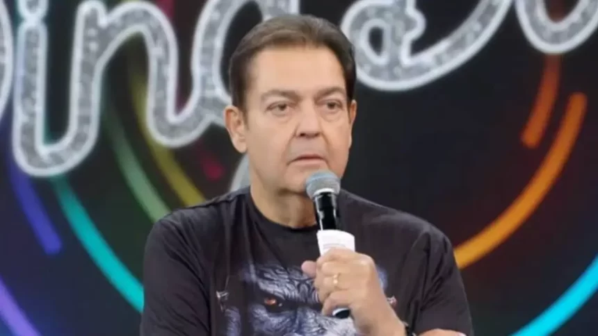 Faustão com microfone na mão apresentando o programa de domingo