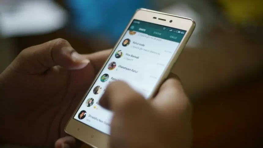 Pessoa segurando um celular aberto no aplicativo WhatsApp
