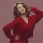 A cantora e atriz Selena Gomez posando de vermelho em uma referência ao seu novo clipe com o noivo