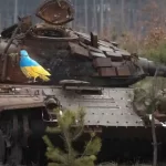 Carcaça de um tanque de guerra destruído mostra um pombo com as cores da bandeira ucraniana e um ramo no bico