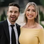 Liam Payne e Kate Cassidy sorrindo e felizes diante de um jardim