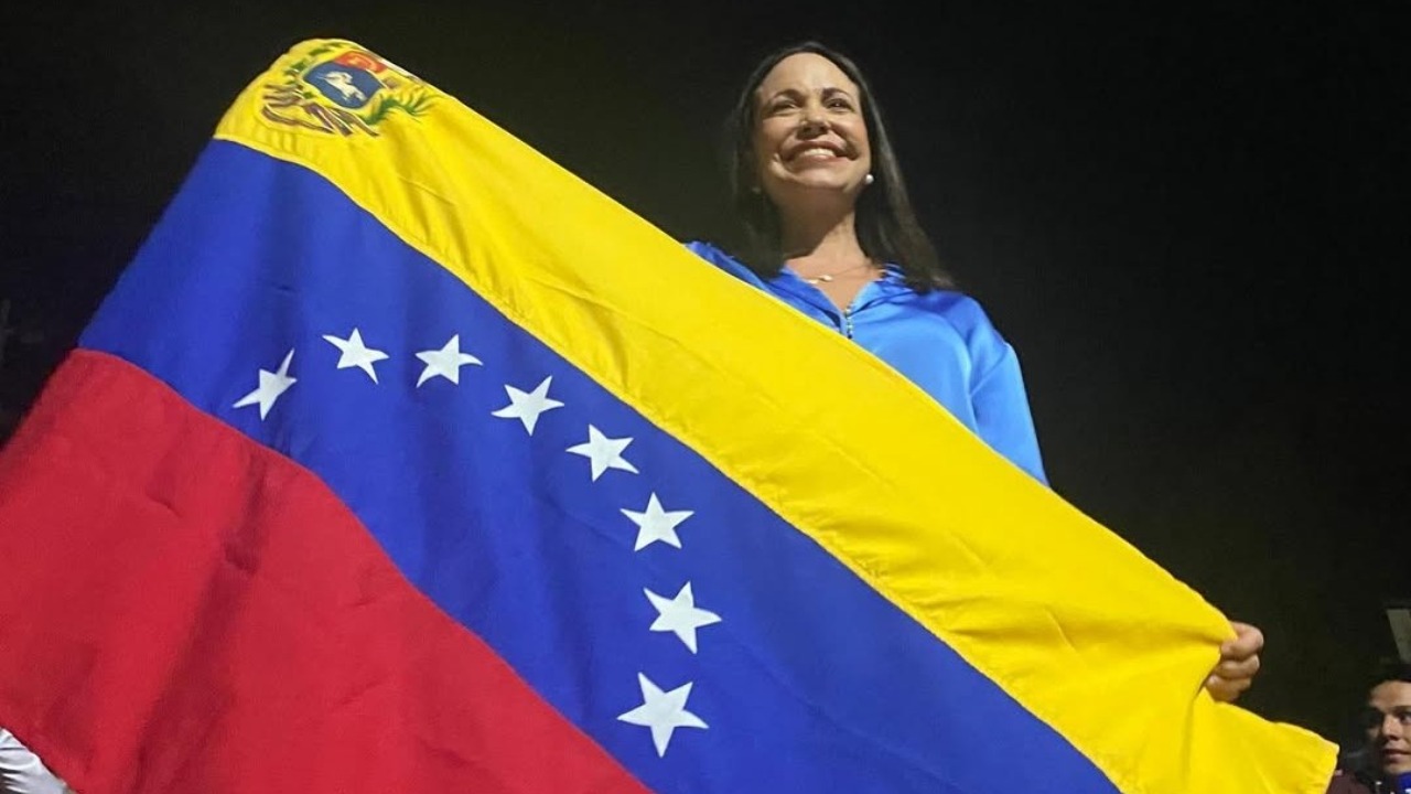 Maria Corina Machado com a bandeira venezuelana| Reprodução/Instagram/@MariaCorinaYa