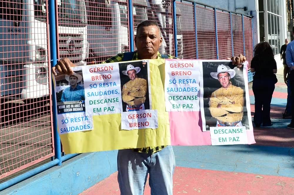 Fã segura cartaz prestando condolências a Gerson Brenner em seu velório