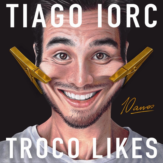 Tiago Iorc celebra 10 anos de “Troco Likes” com álbum repleto de estrelas e anuncia turnê pelo Brasil Capa do álbum "Troco Likes - 10 anos", caricatura de um homem branco com o sorriso sendo puxado por dois prendedores