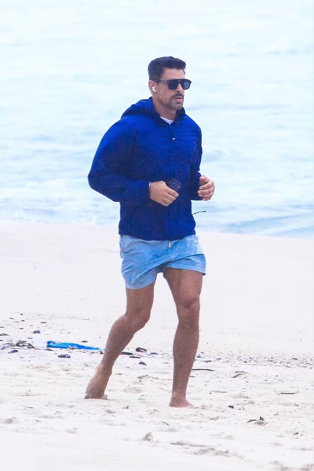 Cauã Reymond chama atenção ao correr na praia bem agasalhado e exibir pernas definidas